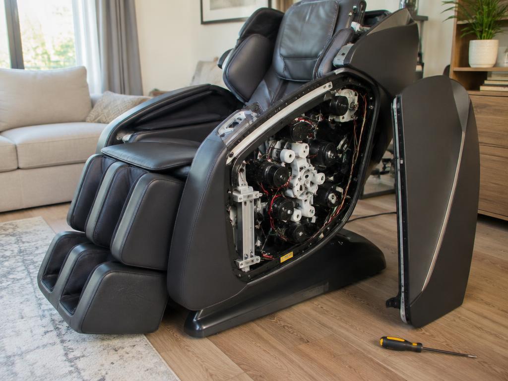 Massage chair with its side panel removed showing internal rollers and motors